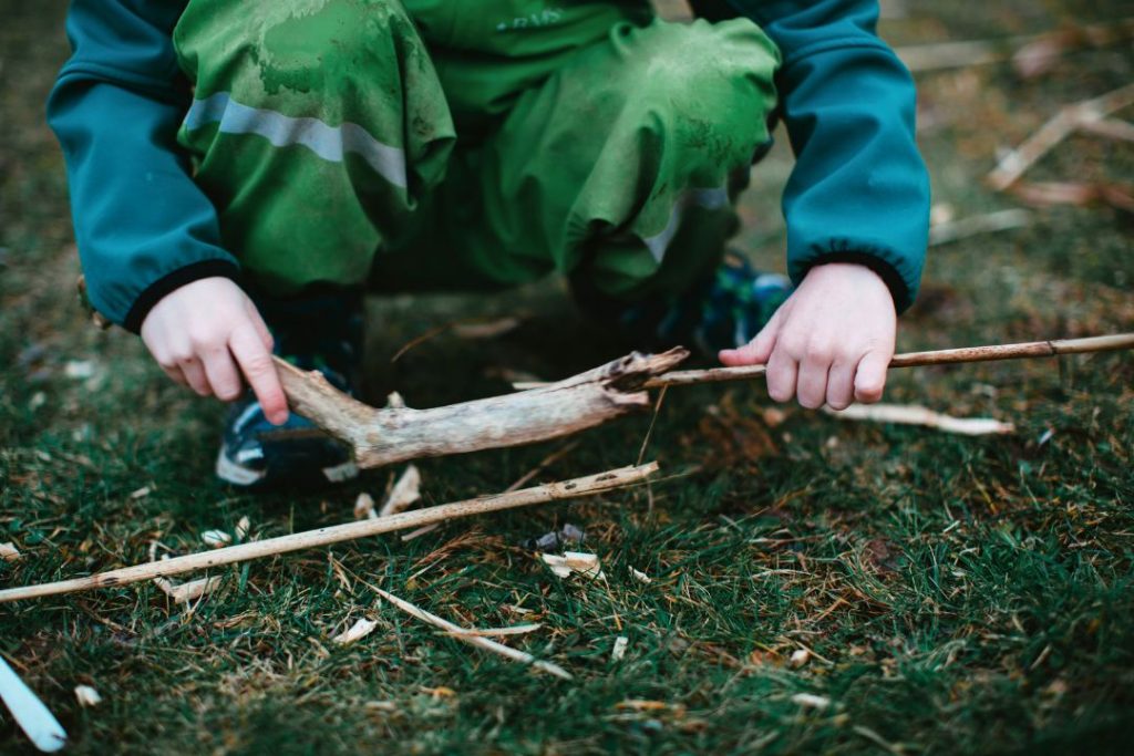 Un enfant qui joue avec des branches en forêt